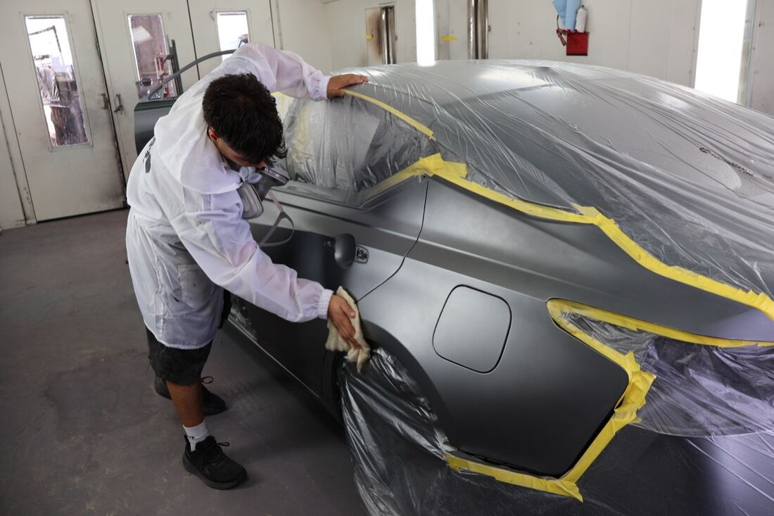 An Apex technician refinishing a panel in the spray booth